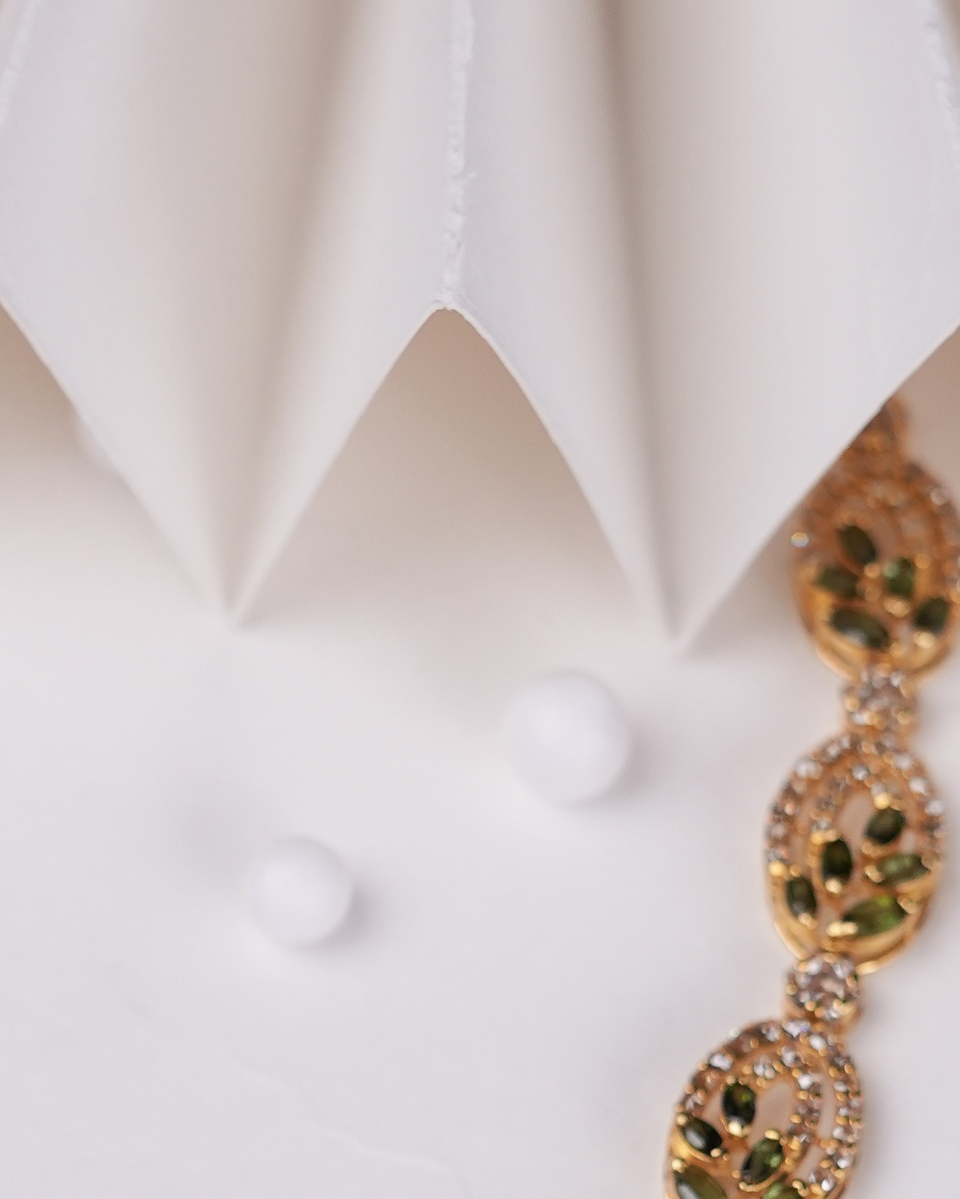 SOL emerald-set bracelet on ivory pleated paper